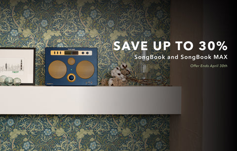 Blue SongBook MAX on a shelf with decorative items against a floral wallpaper background. promo text saying save up to 30%. songbook max. offer ends april 30th.